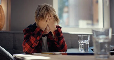 Boy desperately rests his head on his hands Stock Footage 128797361