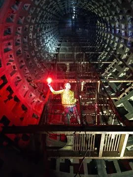 A boy digger poses with a lantern in the perspective of an underground sewage Stock Photos