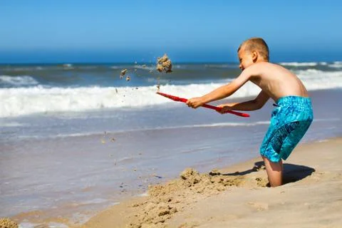Boy digging a hole at the beach Stock Photos