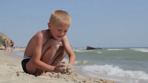 Boy digs sand on the beach Stock Footage 74121737