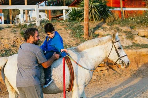 Boy with disability doing mobility exercise during an equine therapy session Stock Photos