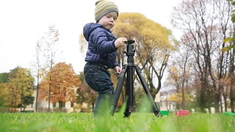 A boy discovers the device of a tripod for a camera Stock Footage 162638090