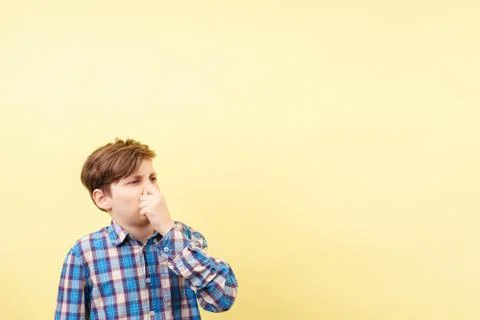 Boy with disgusted face expression covering nose Stock Photos