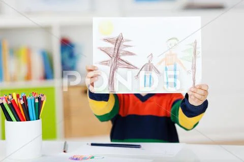 Boy displaying drawing at table Stock Photos