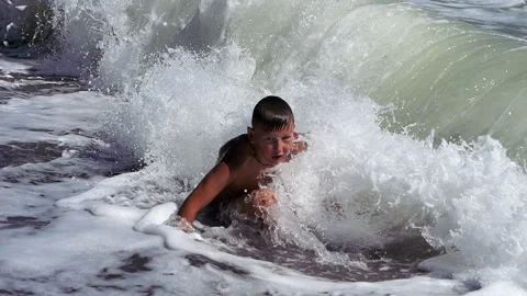 Boy dive into a foaming wave. Live a healthy life. Be H3althy Stock Footage 310058776
