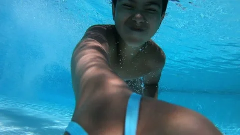 The boy dives into the pool with blue water has fun and swims underwater Stock Footage 236252998