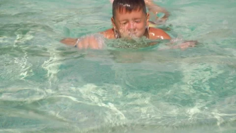 The boy dives in the pool under the water surfacing shows the class.. an Stock Footage 171822837