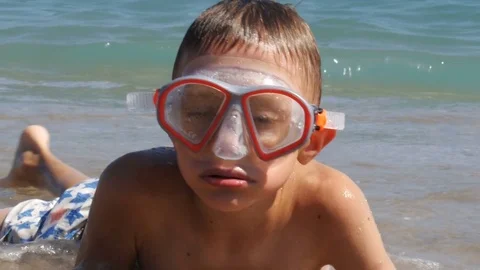 A boy in diving mask lying in sea waves - 4K Stock Footage 80233035