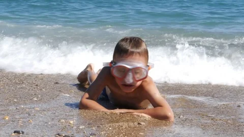 A boy in diving mask lying in sea waves - 4K Stock Footage 80233207