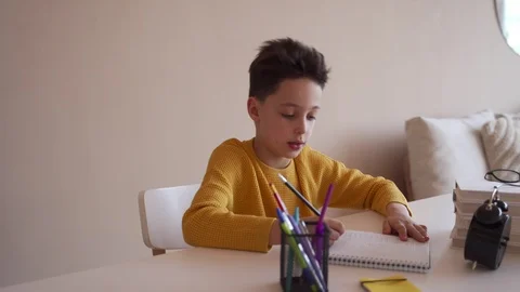 Boy do school homework, writes a ballpoint pen in a notebook. Видео 104238856