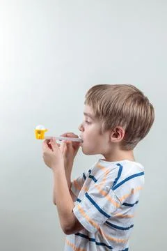The boy does breathing exercises, blows a ball out of a tube. Portrait on a Stock Photos