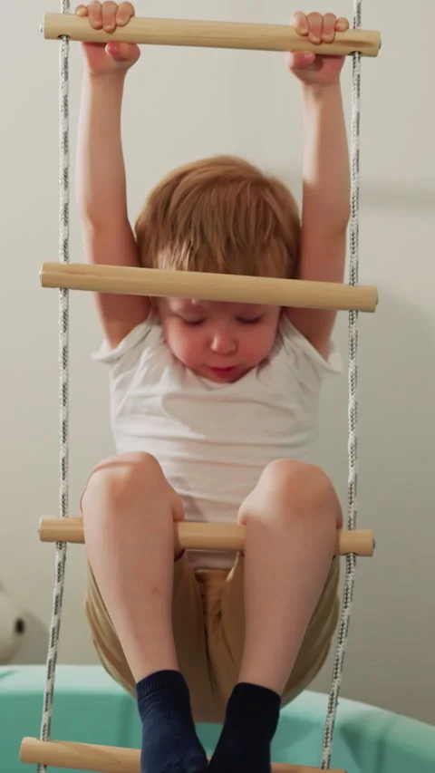 Boy does effort and pulls out legs of rope ladder in gym Stock Footage 307460691