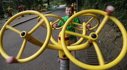 Boy does exercise on a sports simulator in park Stock Footage 49867475