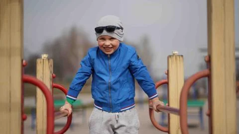 The boy does exercises on parallel bars in the fresh air in the park 写真素材