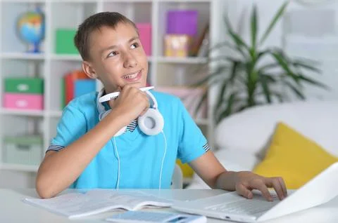 Boy does homework with a laptop at a desk 스톡 사진