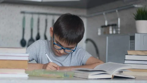 A boy does homework using many textbooks and books. Camera movement Stock Footage 127941371