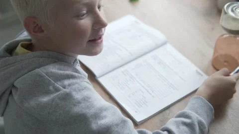 The boy does lessons at home at the table for a while Stock Footage 139740565