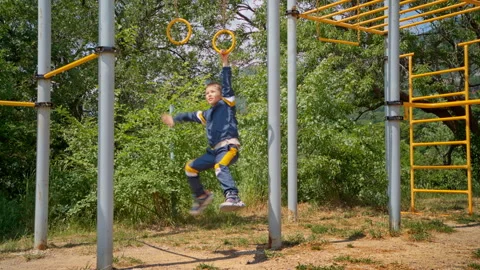 A boy does physical exercises on the hanging rings. Stock Footage 297511681