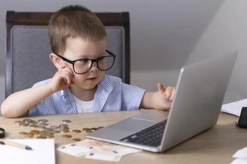The boy does school assignments on a laptop. Stock Photos