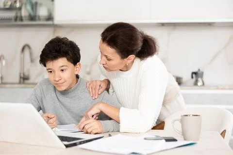 Boy does school homework with his mother and solves mathematical problems in Stock Photos