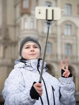 Boy does selfie on phone with self-stick against backdrop landmark building Stock Photos