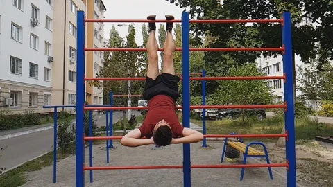 Boy doing abdominal exercises on an outdoor swedish ladder, abs training Stock Footage 94907050