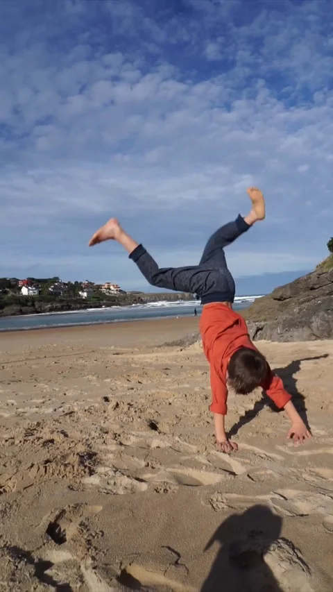 Boy doing cartwheel on the beach Stock Footage 265786836