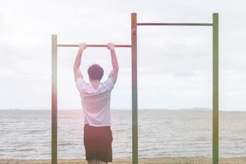 Boy doing exercises on the bar at the beach Stock Photos