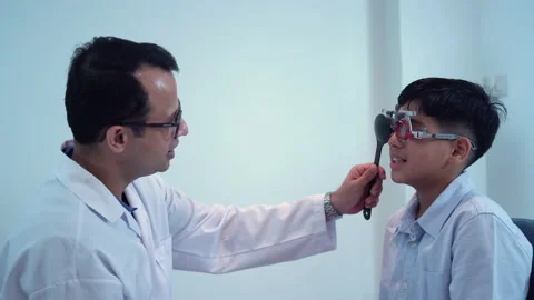 Boy doing eye test checking examination with optometrist in optical shop Stock Footage 165631596