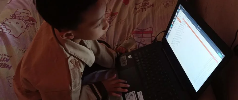 A boy is doing his schoolwork using a laptop Stock Photos