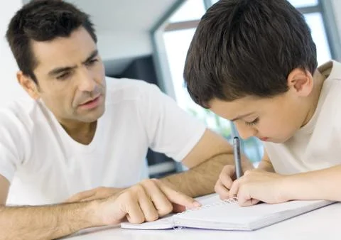 Boy doing homework with father's help, cropped Stock Photos