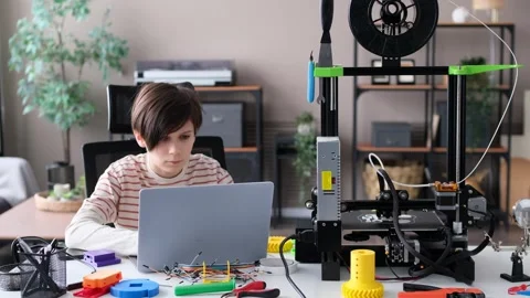 Boy Doing Homework With Laptop And 3D Printer Stock Footage 266788352