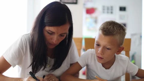Boy doing homework with mother Stock Footage 290088828