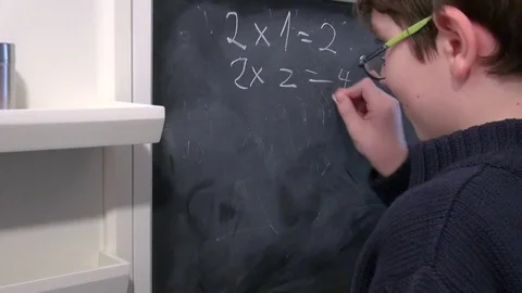 Boy doing math on a chalkboard at school Stock Footage 71962807