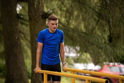 Boy doing parallel bar dips outdoors. Summer sports activity. Stock Photos