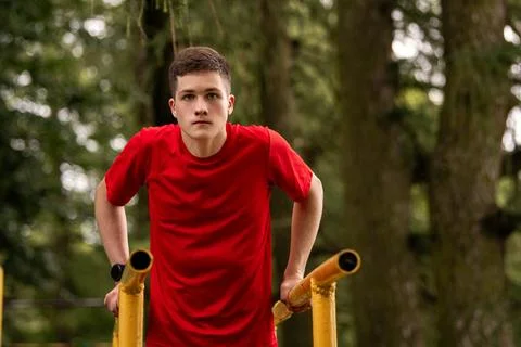 Boy doing parallel bar dips outdoors. Summer sports activity. Stock Photos