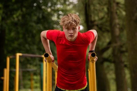Boy doing parallel bar dips outdoors. Summer sports activity. Stock-Fotos