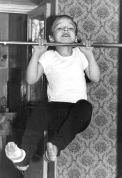 Boy doing pull-up on bar in soviet apartment 1960s Stock Photos