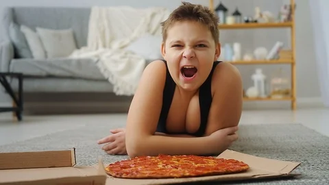 Boy doing push-UPS from the floor where the pizza is Stock Footage 108149882