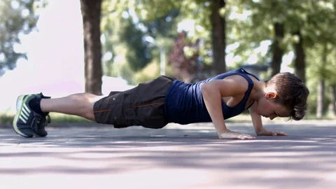 Boy doing push-ups sport exercise in park Stock Footage 116090073