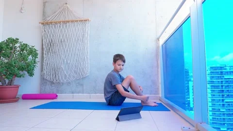 Boy doing sport exercises while watching video lesson online on tablet computer Stock Footage 132913838