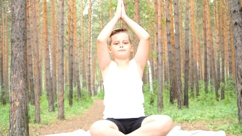 Boy doing yoga in the woods Stock Footage 122120682