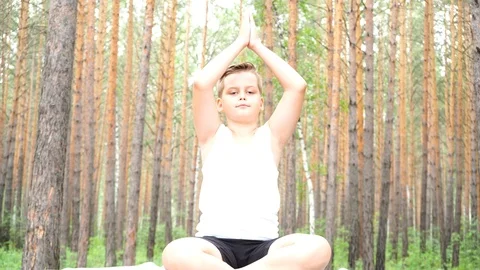 Boy doing yoga in the woods Stock Footage 122120713