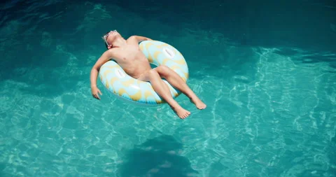 Boy, donut and kid floating in pool water, freedom and summer break for peace on Stock Footage 301039086