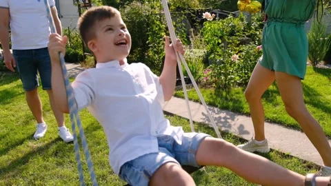 A boy with Down syndrome having fun on a swing with his father. Stock Footage 165042768