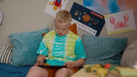 Boy with Down Syndrome Interacting with Digital Tablet at Home Stock Footage 337567798