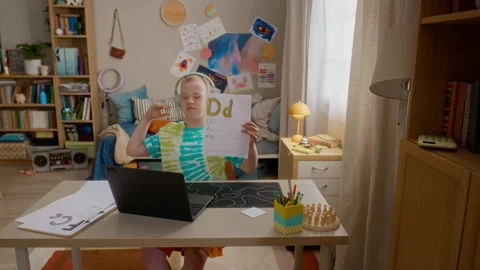 Boy with down Syndrome Showing Alphabet Sheet during Online Lesson Stock Footage 337570071