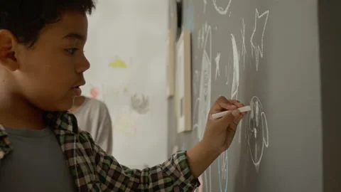 Boy Drawing on Blackboard with Chalk at Home, Elder Brother Watching Stock Footage 342501412