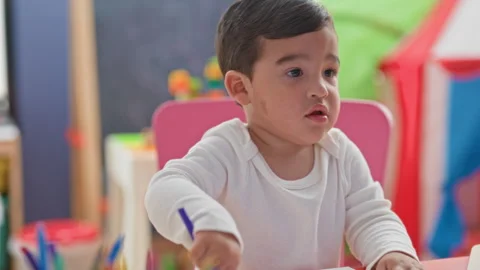 Boy drawing with blue marker, hand on paper at table in studio; concentrati.. Stock Footage 339186411