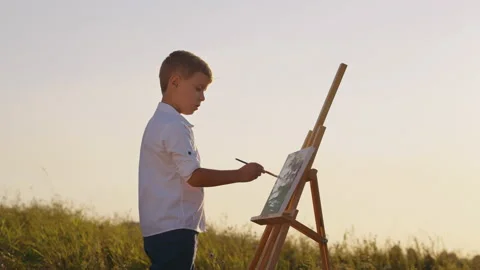 Boy drawing on canvas in open air Stock Footage 158157298